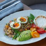 Delicious quinoa salad with sliced avocado, soft-boiled eggs, and fresh herbs.
