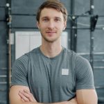 Portrait of young sportsman in sportswear standing in gym with arms crossed and looking at camera feeling confident and ambitious. People and sports concept.